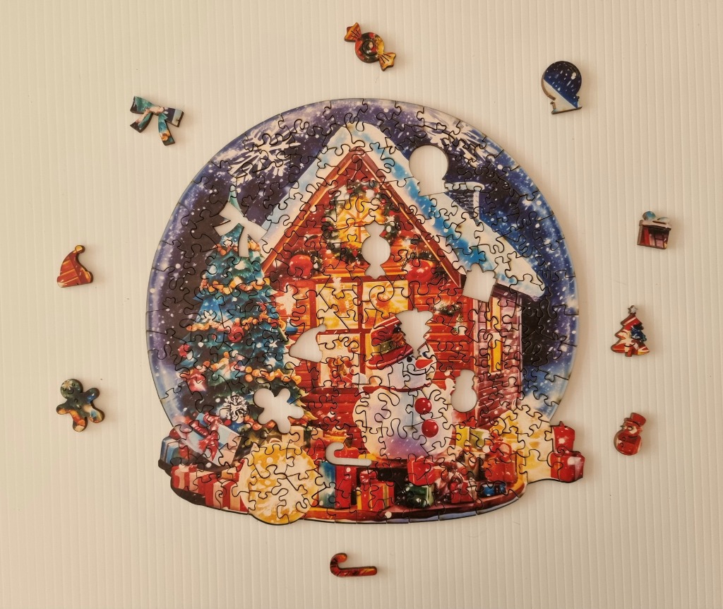 A whimsical snow globe illustration featuring a festive cottage, a snowman, and Christmas decorations.