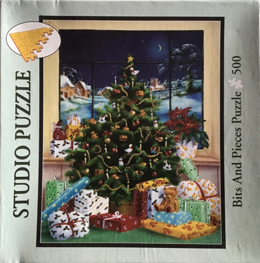 Christmas tree with presents in front of a window overlooking a snowy village at night.
