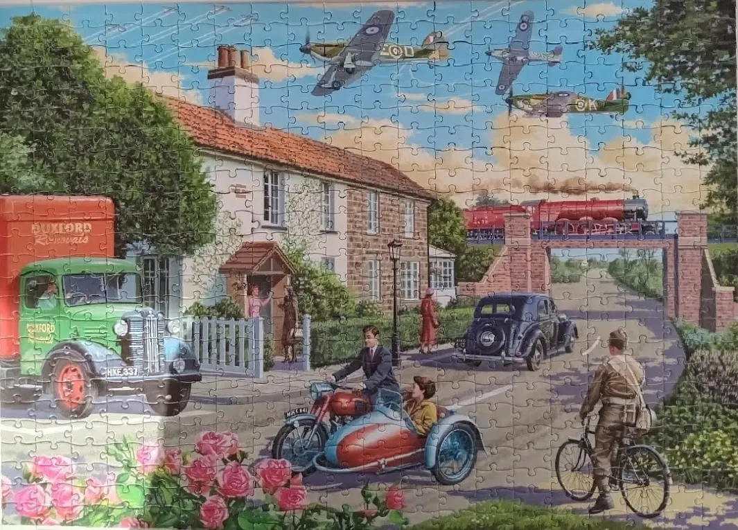 A nostalgic rural British street scene featuring vintage vehicles, a house, and fighter planes overhead.