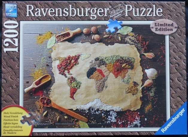 A world map created from various colorful spices arranged on a piece of parchment paper atop a wooden table.