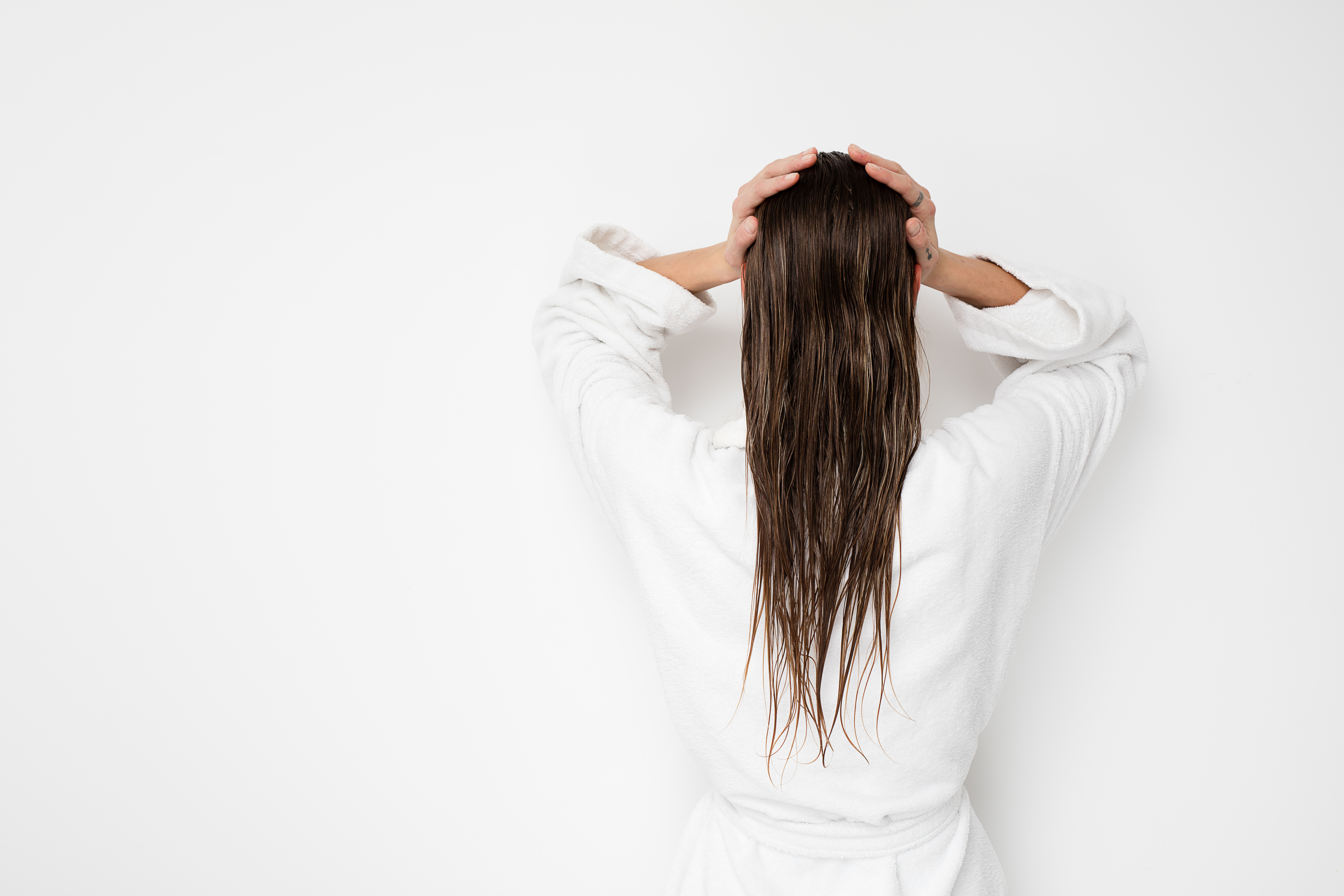 Image of a woman wearing a white bath robe holding her long hair.
