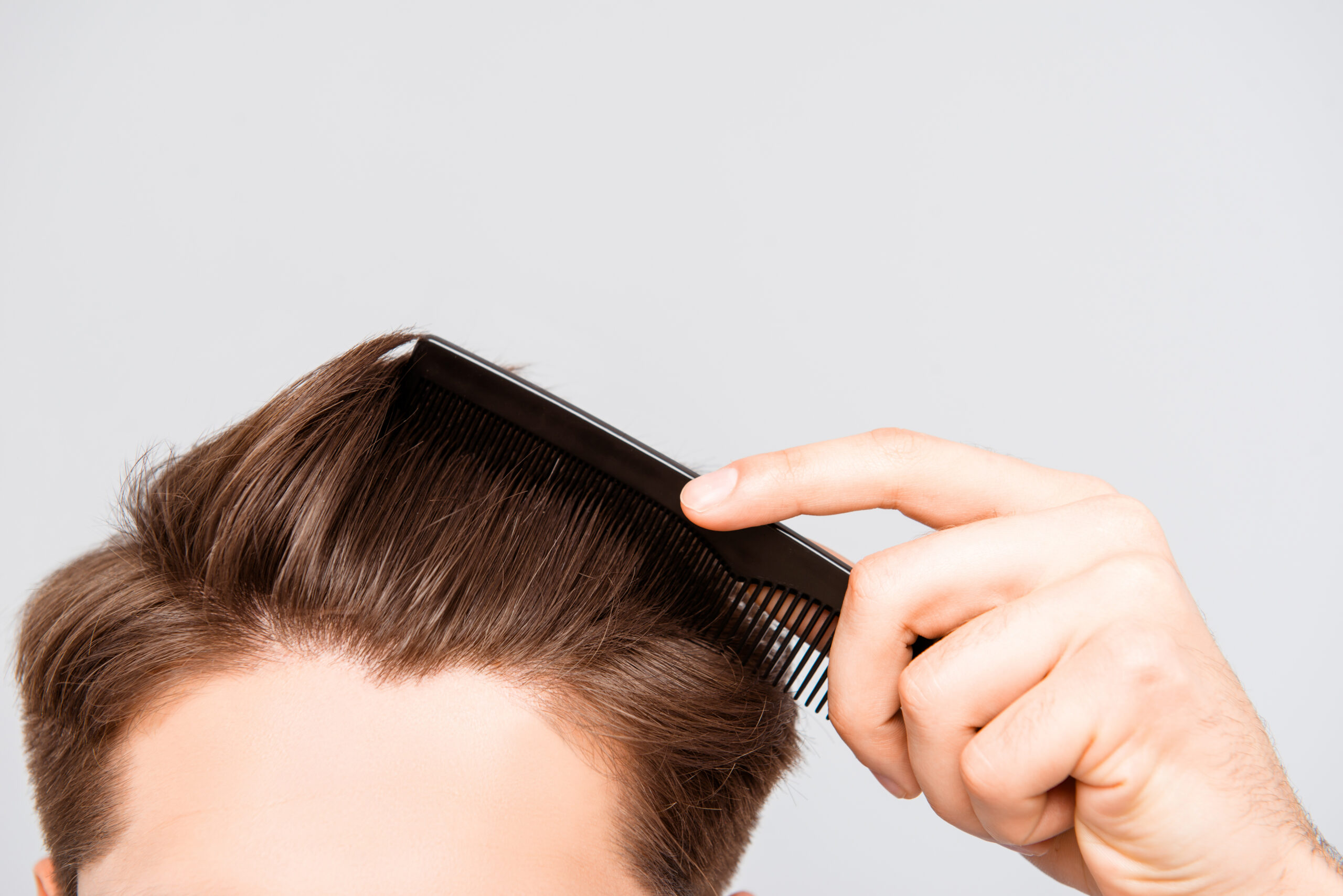 Image shows a close up shot of a man combing his hair.