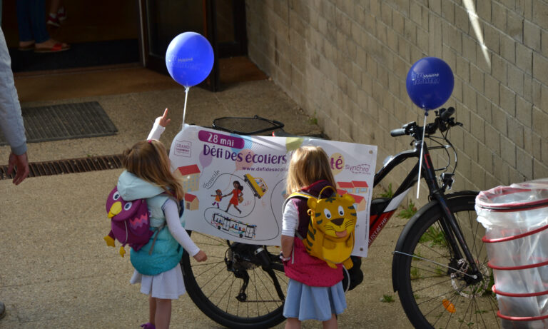 Photo d'élèves à côté d'un vélo qui a une affiche pour le défi des écoliers