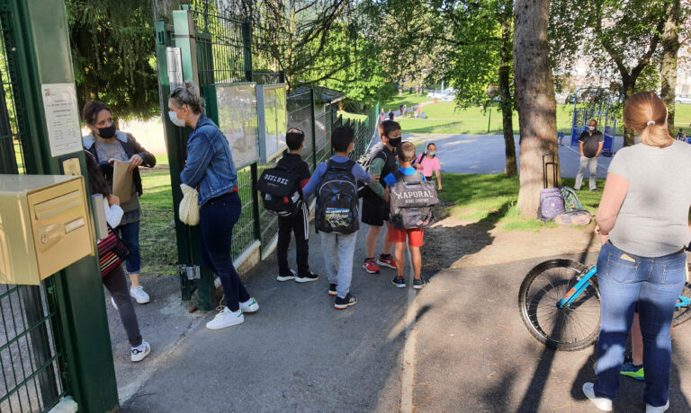 Photo d'une entrée d'une école avec des personnes