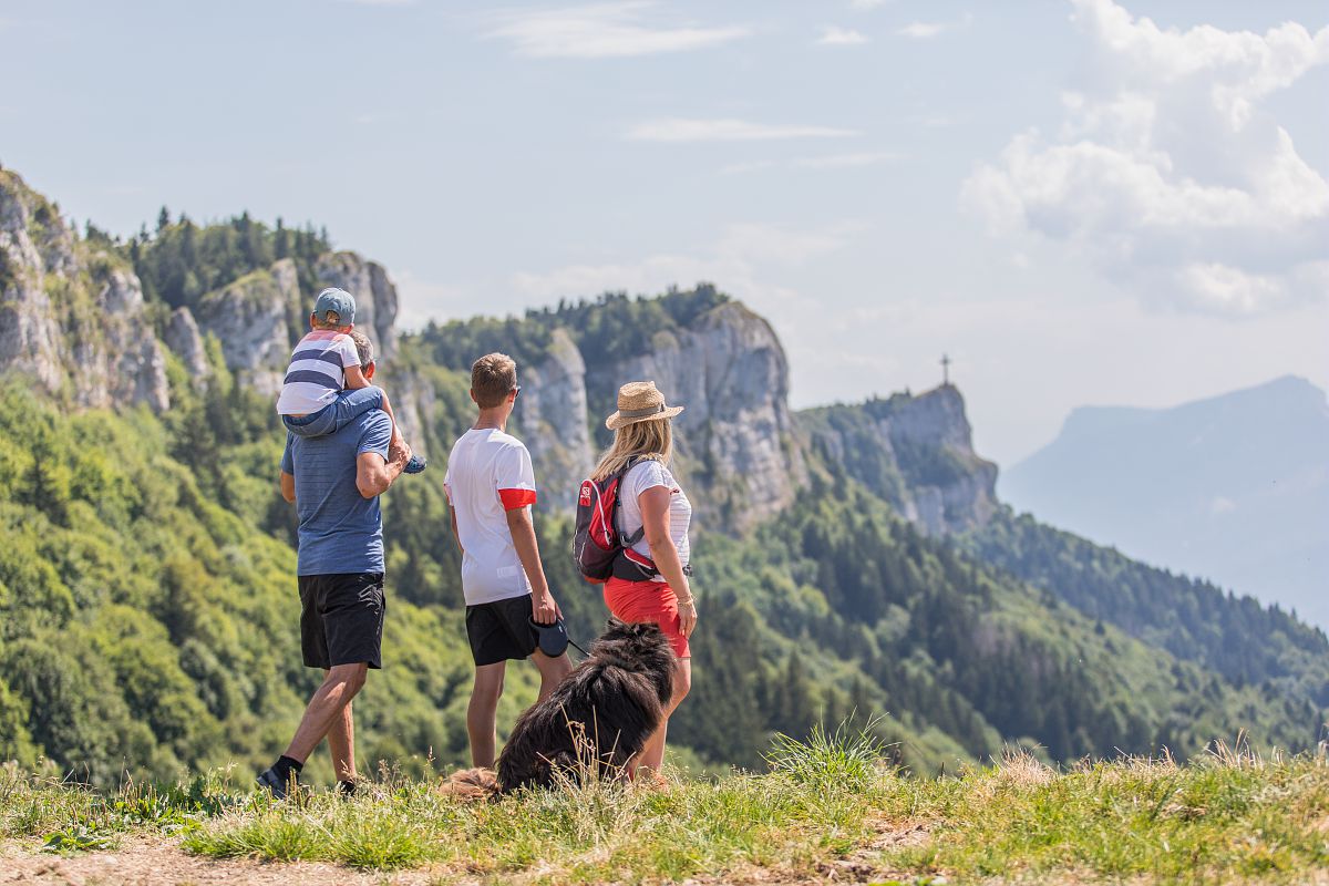 Photo d'une famille avec un chien en train de regarder au loin la Croix du Nivolet