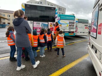 Visite du dépôt de bus Synchro Bus. Des enfants et des accompagnateurs visitant le dépôt de bus de Chambéry avec des gilets orange.