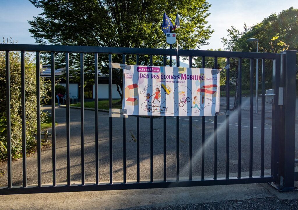 Photo d'une affiche du Défi des écoliers mise sur un grillage d'école 10ème édition