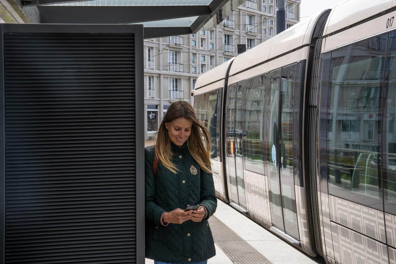 Femme qui utilise l'application Atoumod sur le quai d'un tramway en Normandie.