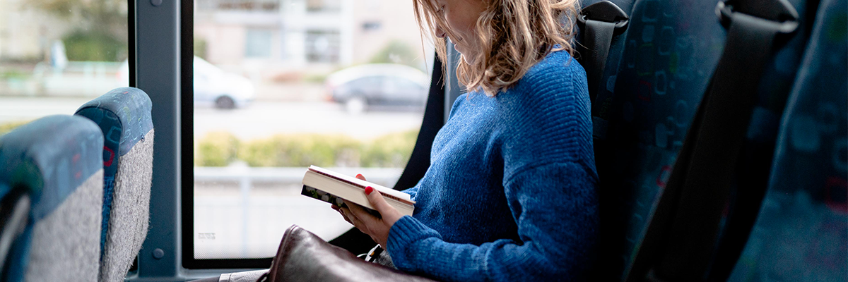 Jeune femme lit un livre dans le bus