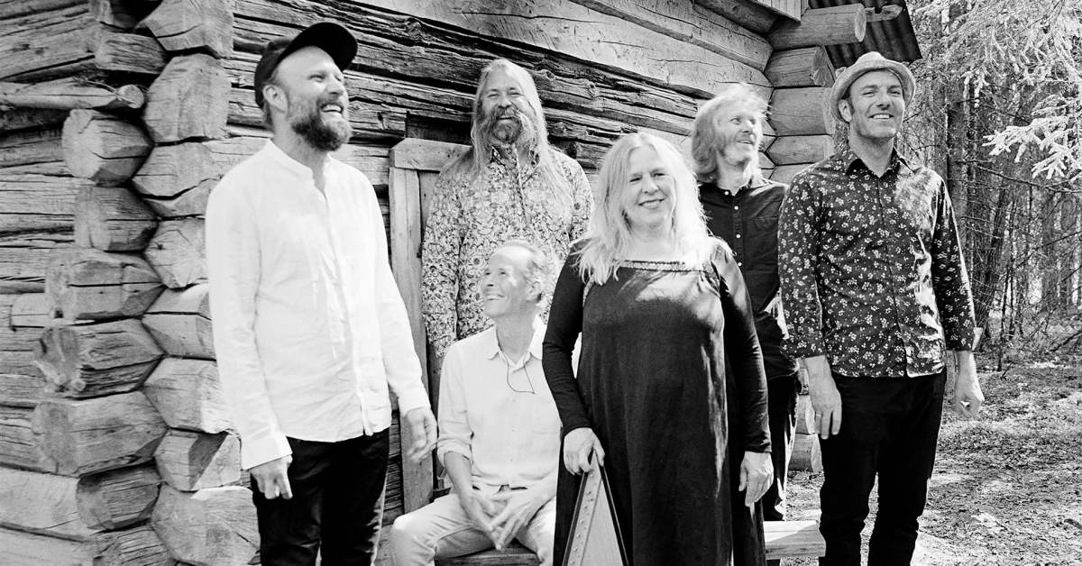 Et bandbilde i svart og hvitt. 5 menn og en kvinne som holder i et gammelt strenginstrument smiler.