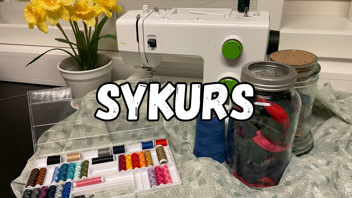 Bilde av en symaskin med et lyseblått stoff og fargerike sytråder. To krukker med symatriell og en gul blomst ved siden av.