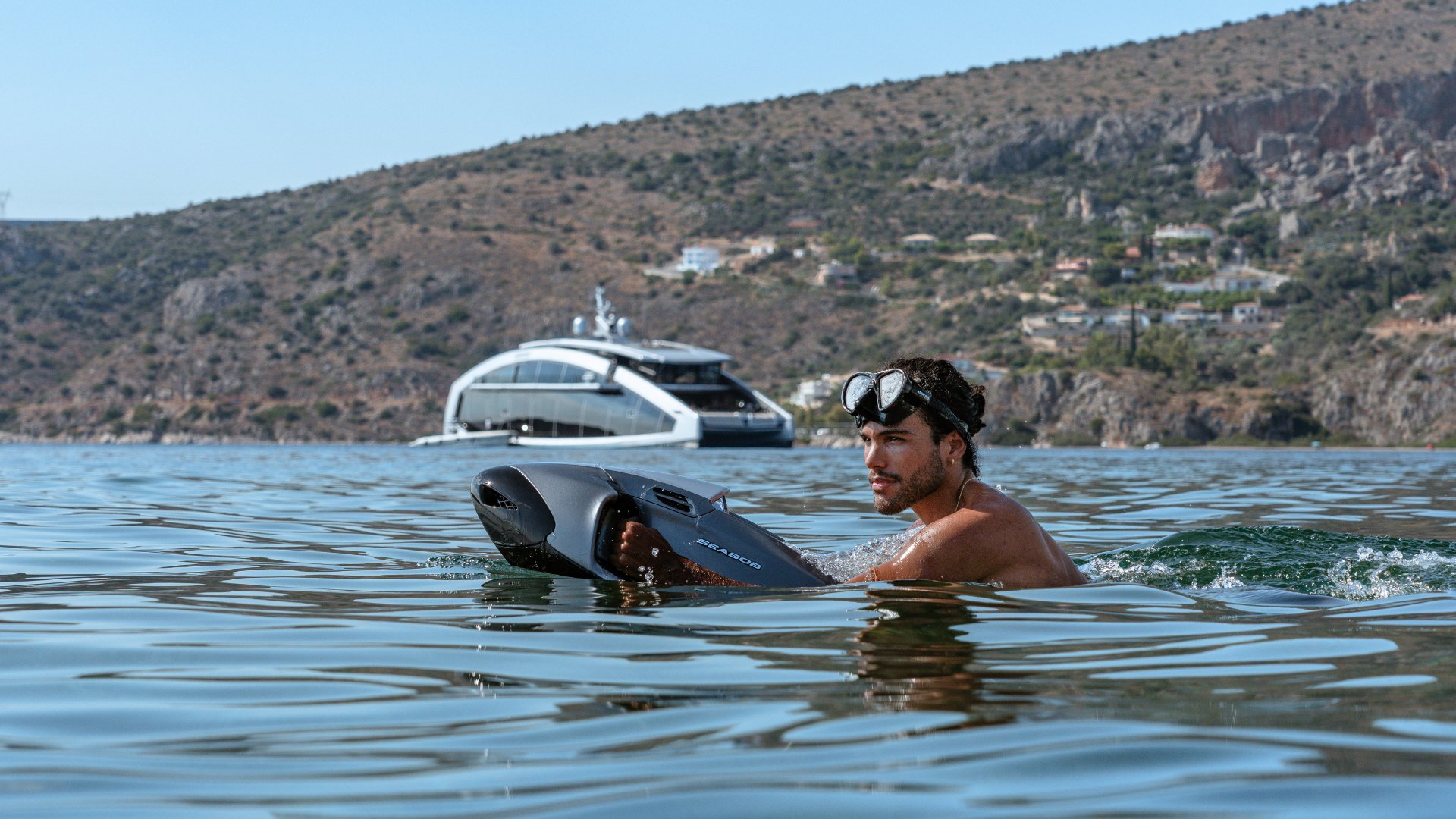 a man riding a seabob in greece with the iyc yacht this is it in the background