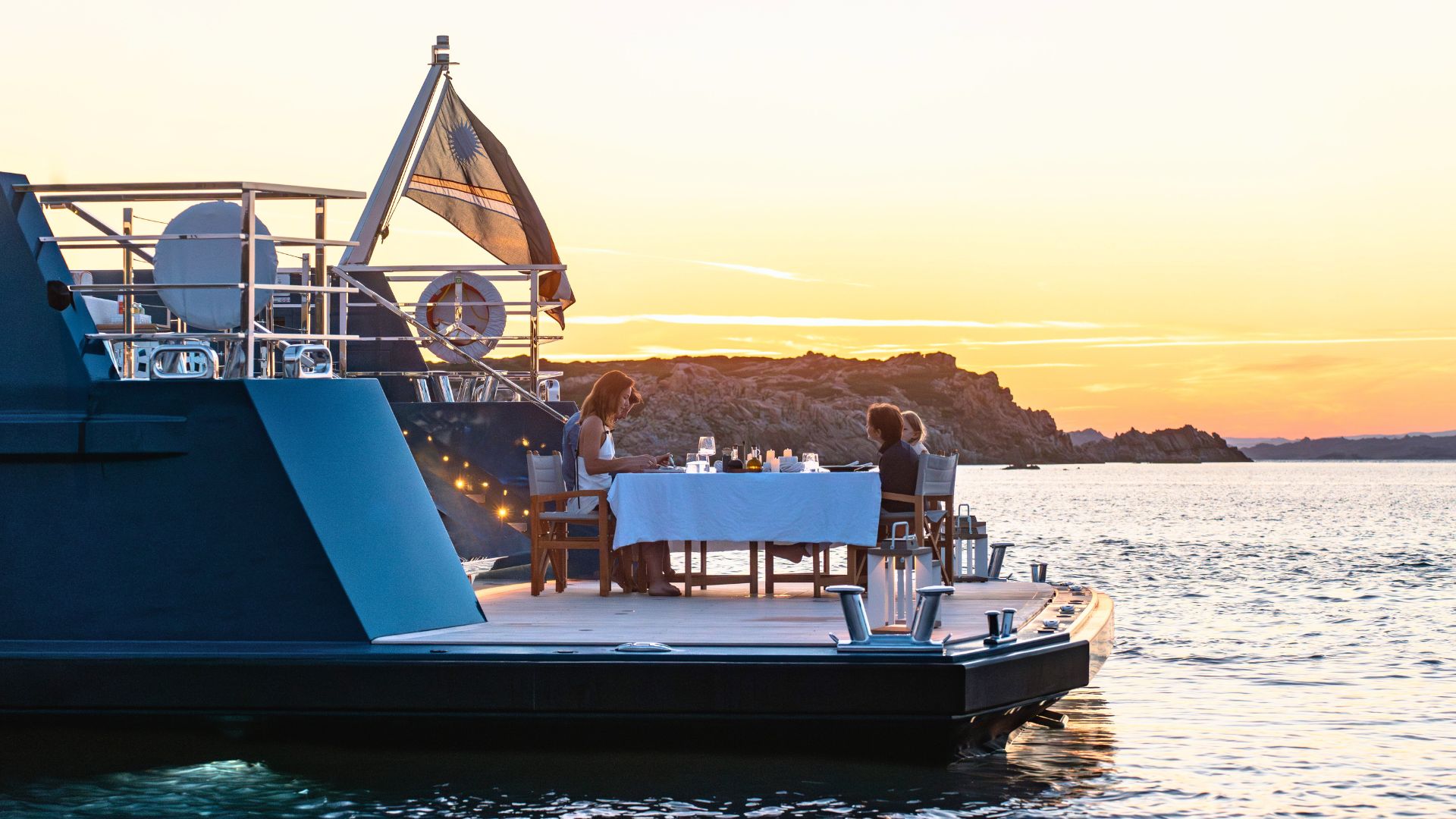 a family having dinner at the platform of a yacht during sunset