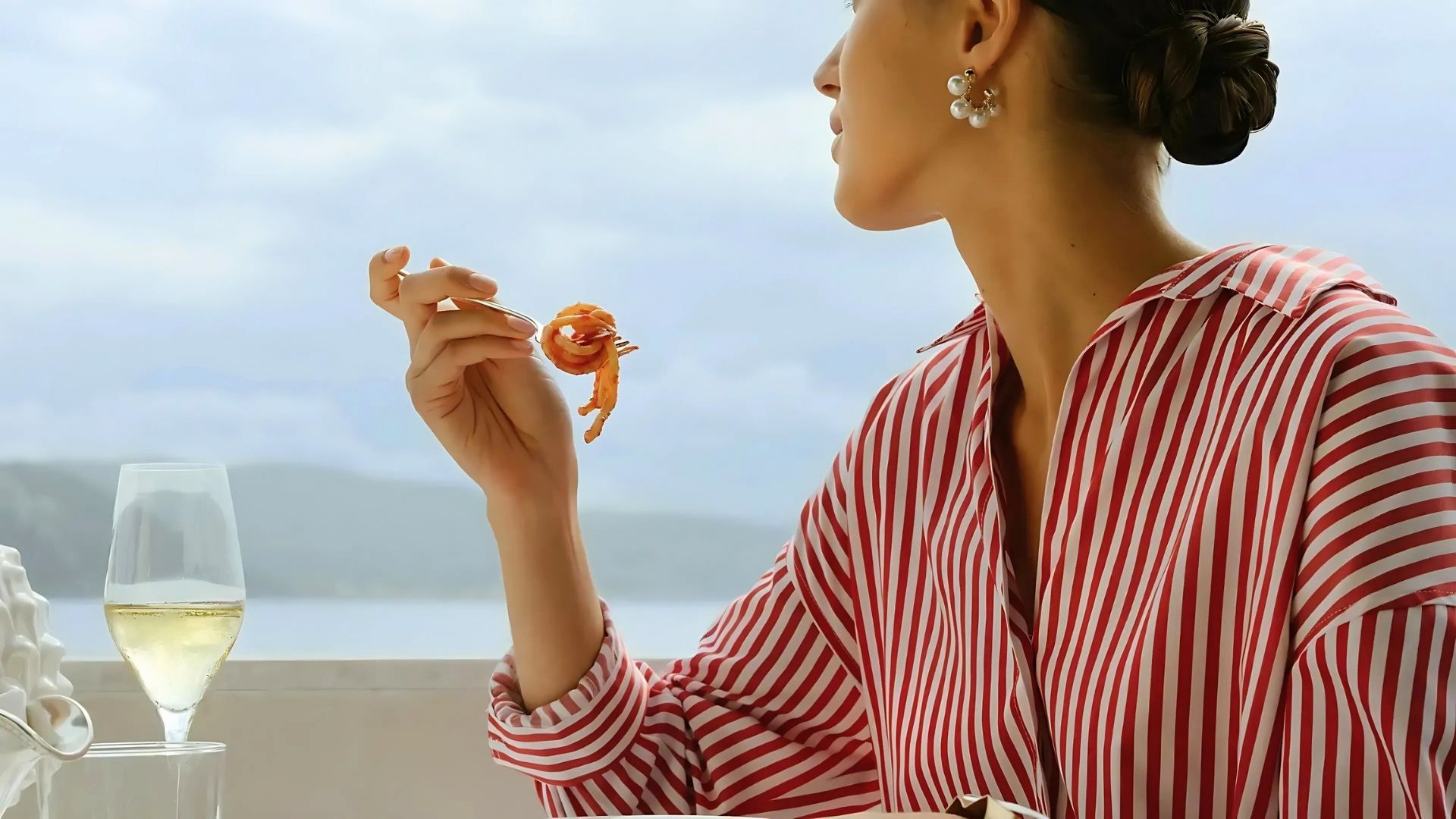 a female eating seafood and having wine while gazing the sea view at restaurant vistamare italy