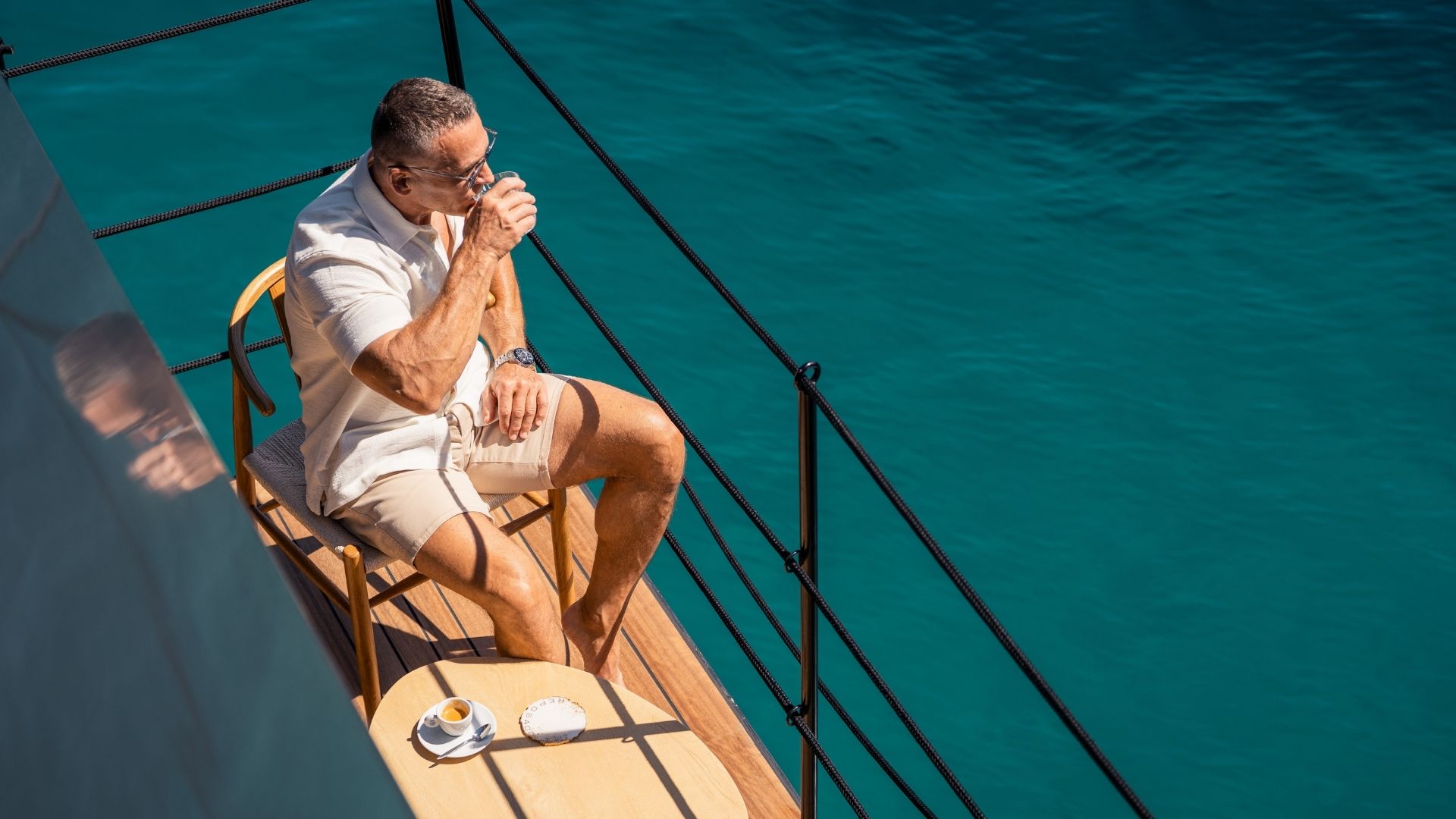 a man having coffee on the fold down balcony of the iyc yacht reposado