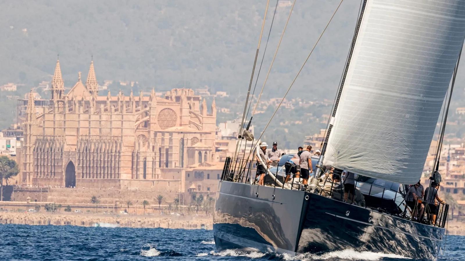 a sailing yacht at the palma superyacht cup with palma on the background