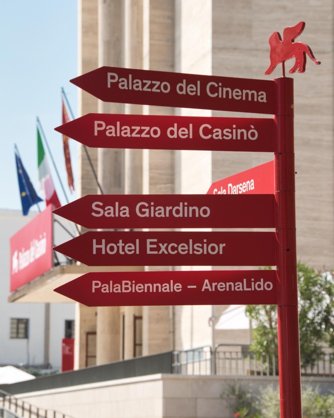 a red sign giving directions to the venues of the venice film festival