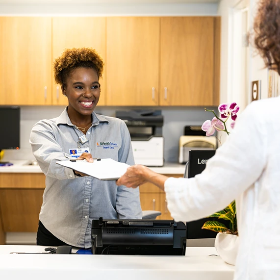 A woman smiling as she hands a document to a person