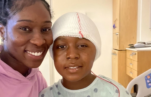 boy with bandages on his head posing next to his mom