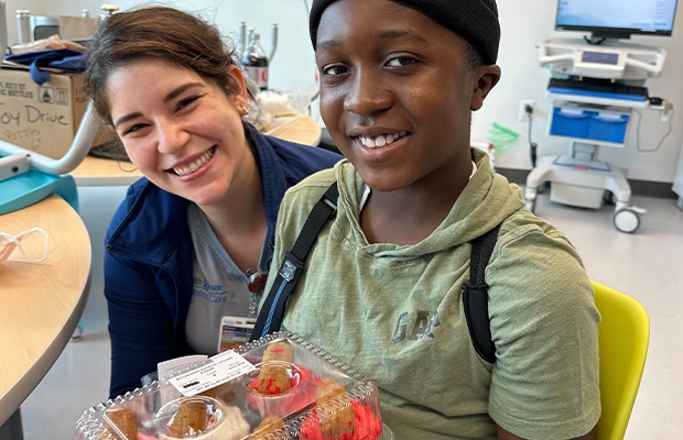 boy next to his nurse holding a dessert