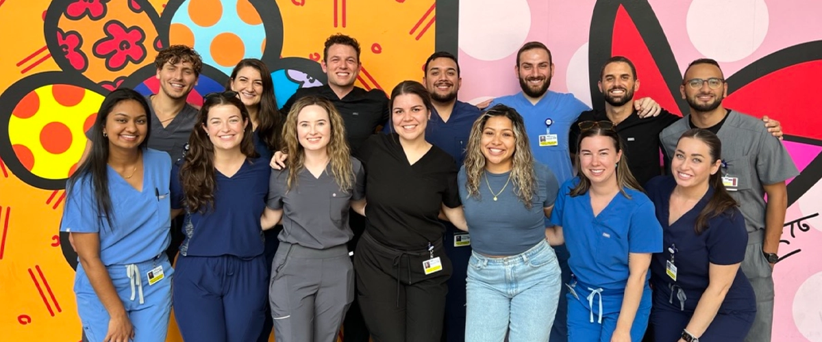 A group of doctors hugging in front of a colorful wall.
