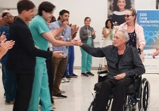 Man in a wheelchair high-fiving hospital doctors.