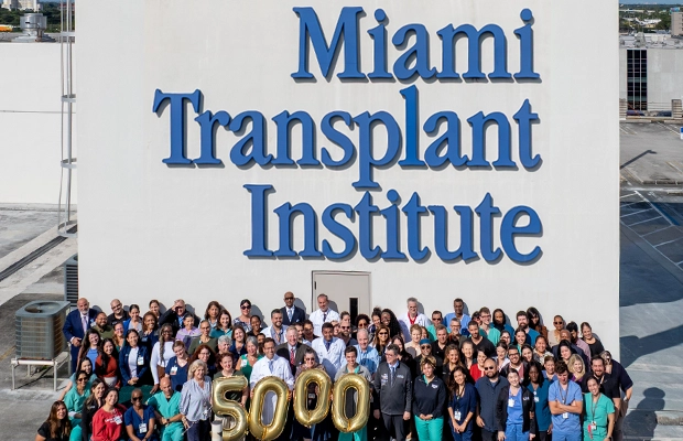 Large group of people posing next to a face with a Jackson Health sign