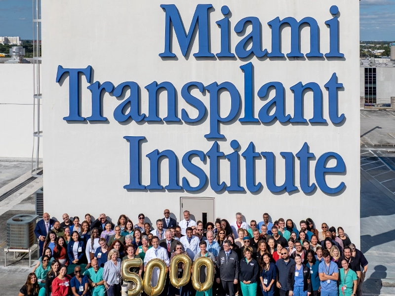 Large group of people posing next to a face with a Jackson Health sign