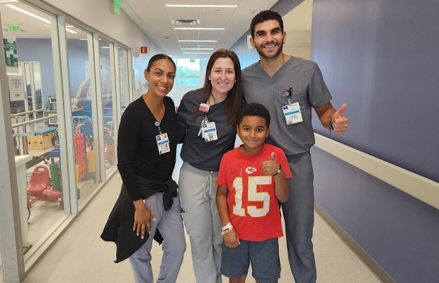 A boy smiling next to two women and his doctor.