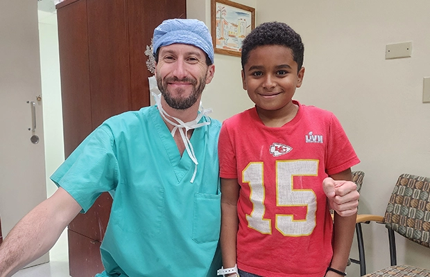 Boy posing and smiling next to a doctor.