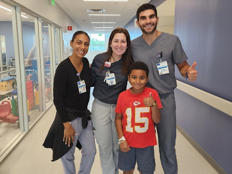 A boy smiling next to two women and his doctor.