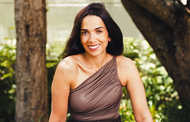 Close-up of a woman with black hair and a brown blouse smiling at the camera.