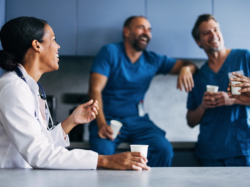 A group of doctors smiling and talking while having a hot drink
