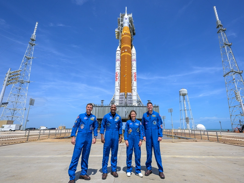 Photograph of 4 astronauts in front of a space rocket