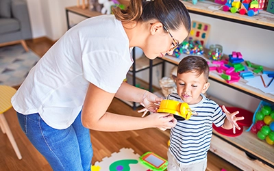 woman and child playing in a living room full of toys