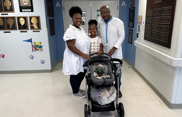 Man, woman and girl holding a small baby