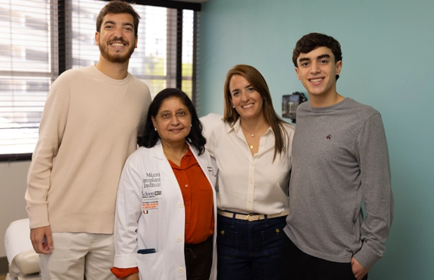 Two men and a woman posing alongside their doctor.