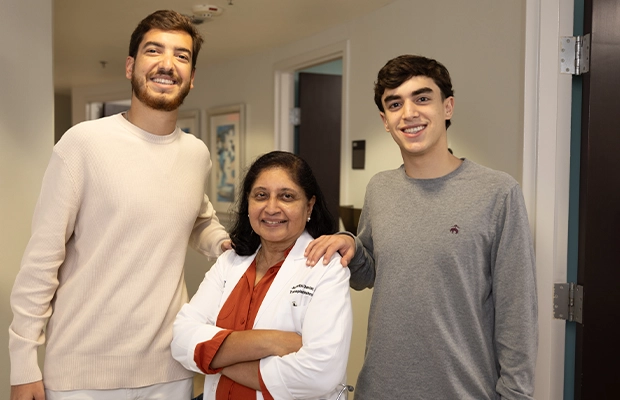 Two men posing alongside their doctor.