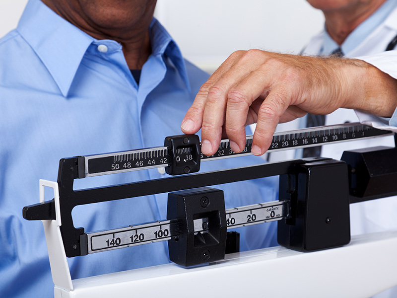 Closeup of a man getting his weight checked by a physician