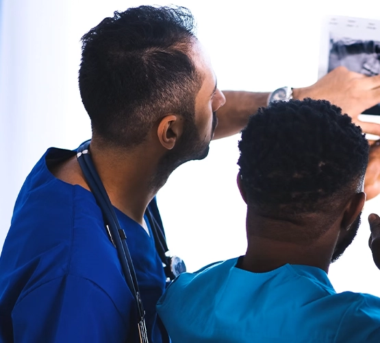 Two doctors with their backs to each other checking a screen