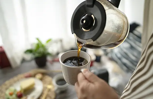 A closeup of a person pouring coffee into a cup