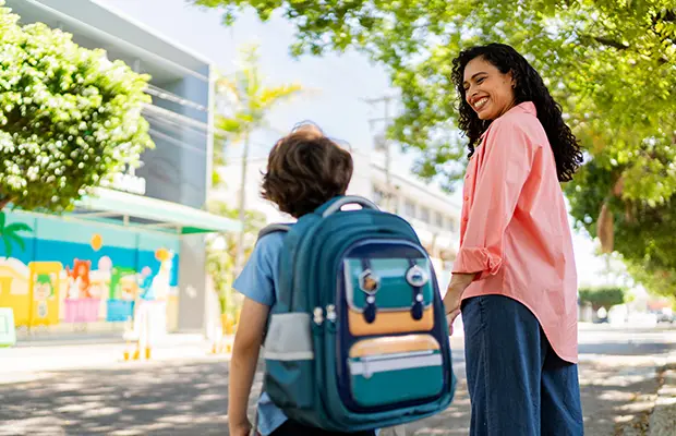 A mom and young boy walking, he has a backpack on