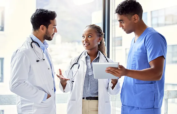 Three medical professionals standing and looking at each other, they are having a discussion