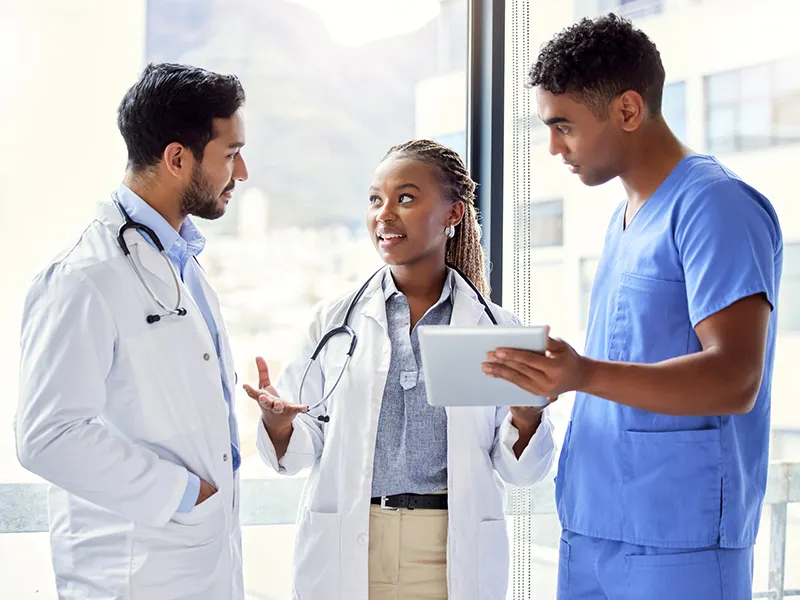 Three medical professionals standing and looking at each other, they are having a discussion