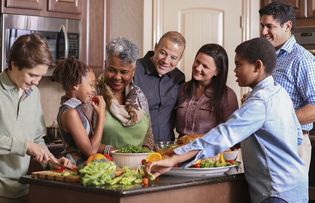 A family standing around a kitchen island, they're putting together a salad