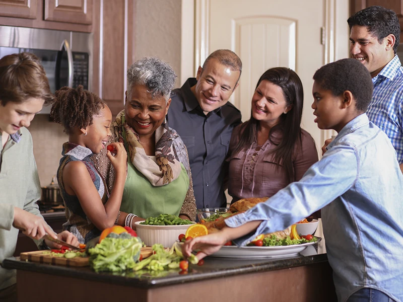 A family standing around a kitchen island, they're putting together a salad