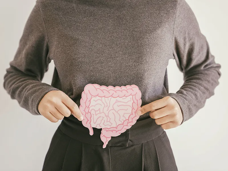A closeup of a woman holding a cutout of a stomach