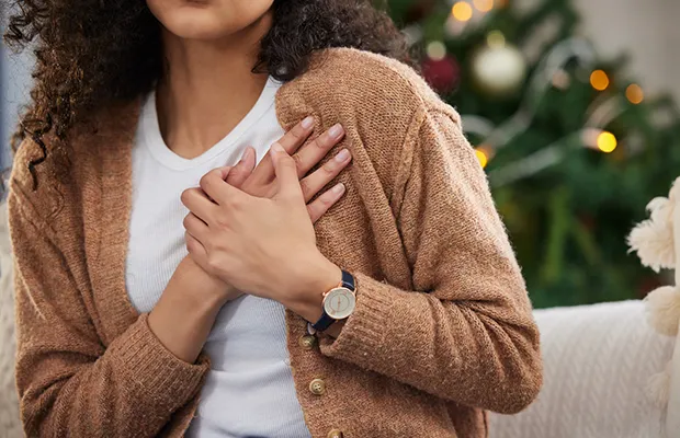 A closeup of a women holding her hands over her left side of her chest