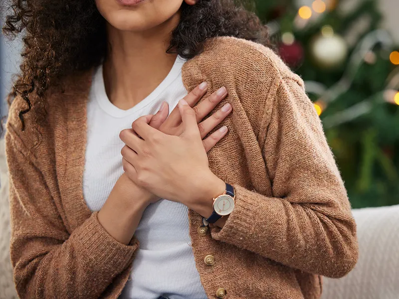 A closeup of a women holding her hands over her left side of her chest