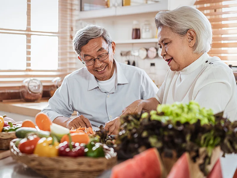 An older couple prepping vegetables in the kitchen